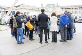 Blick von hinten auf die Kooperationspartner:innen bei einer Pressekonferenz am Heldenplatz, während Medienvertreter:innen die Situation dokumentieren © MKÖ/Alissar Najjar