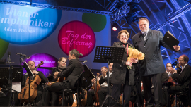 Lucia Heilmann hält den ihr überreichten Blumenstrauß und steht neben Willi Mernyi auf der Bühne. Fest der Freude 2017 © MKÖ/Sebastian Philipp  